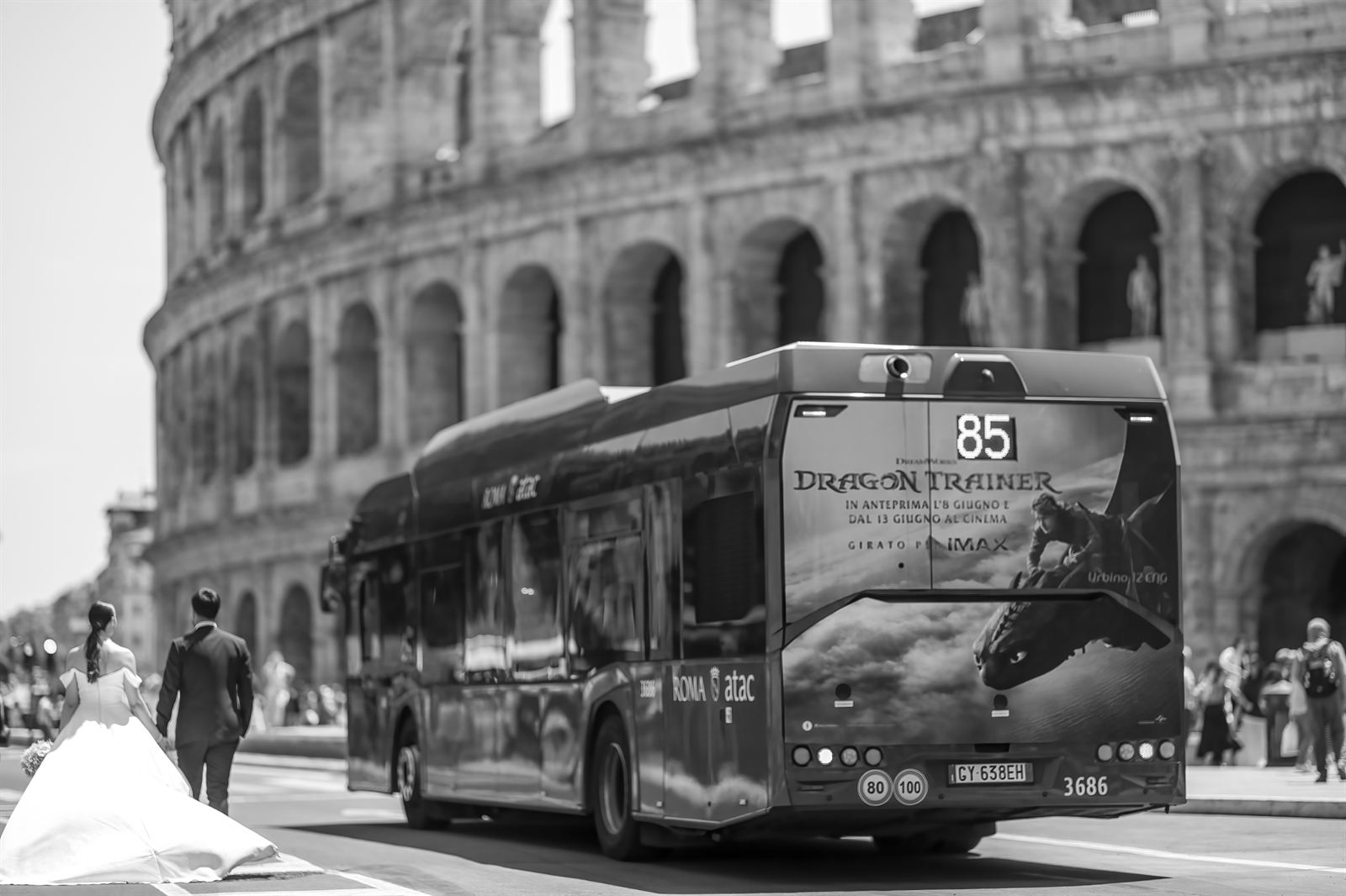 Sposi davanti al Colosseo mentre passa un autobus, in bianco e nero