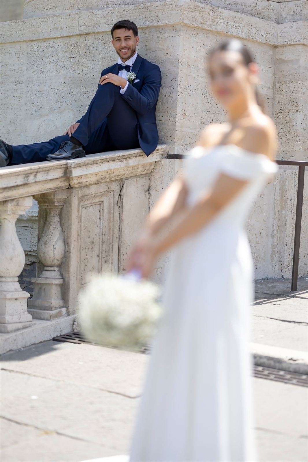 Lo sposo seduto sulla balaustra e la sposa sfocata in primo piano