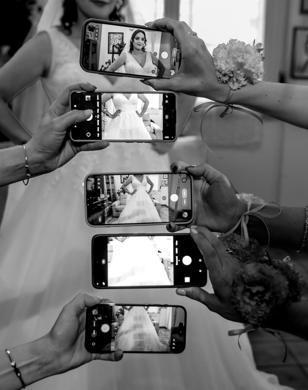 Gli invitati fotografano la sposa con lo smartphone, in bianco e nero
