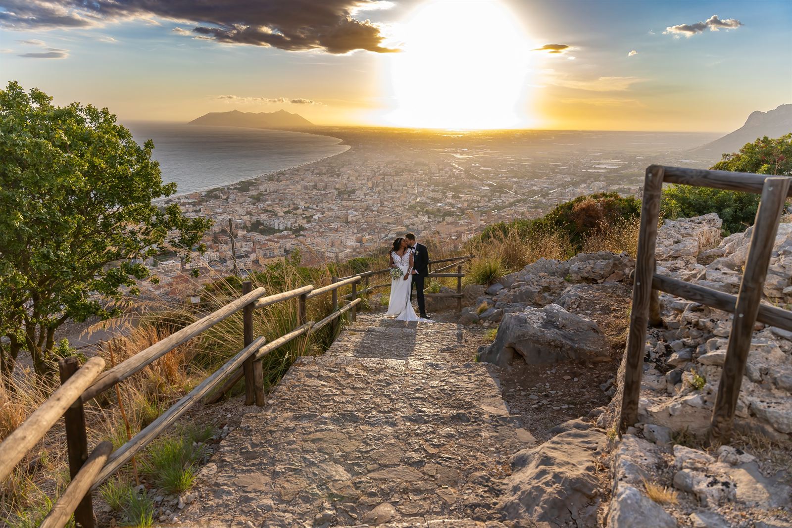 Sposi su un sentiero panoramico al tramonto, con vista sul mare