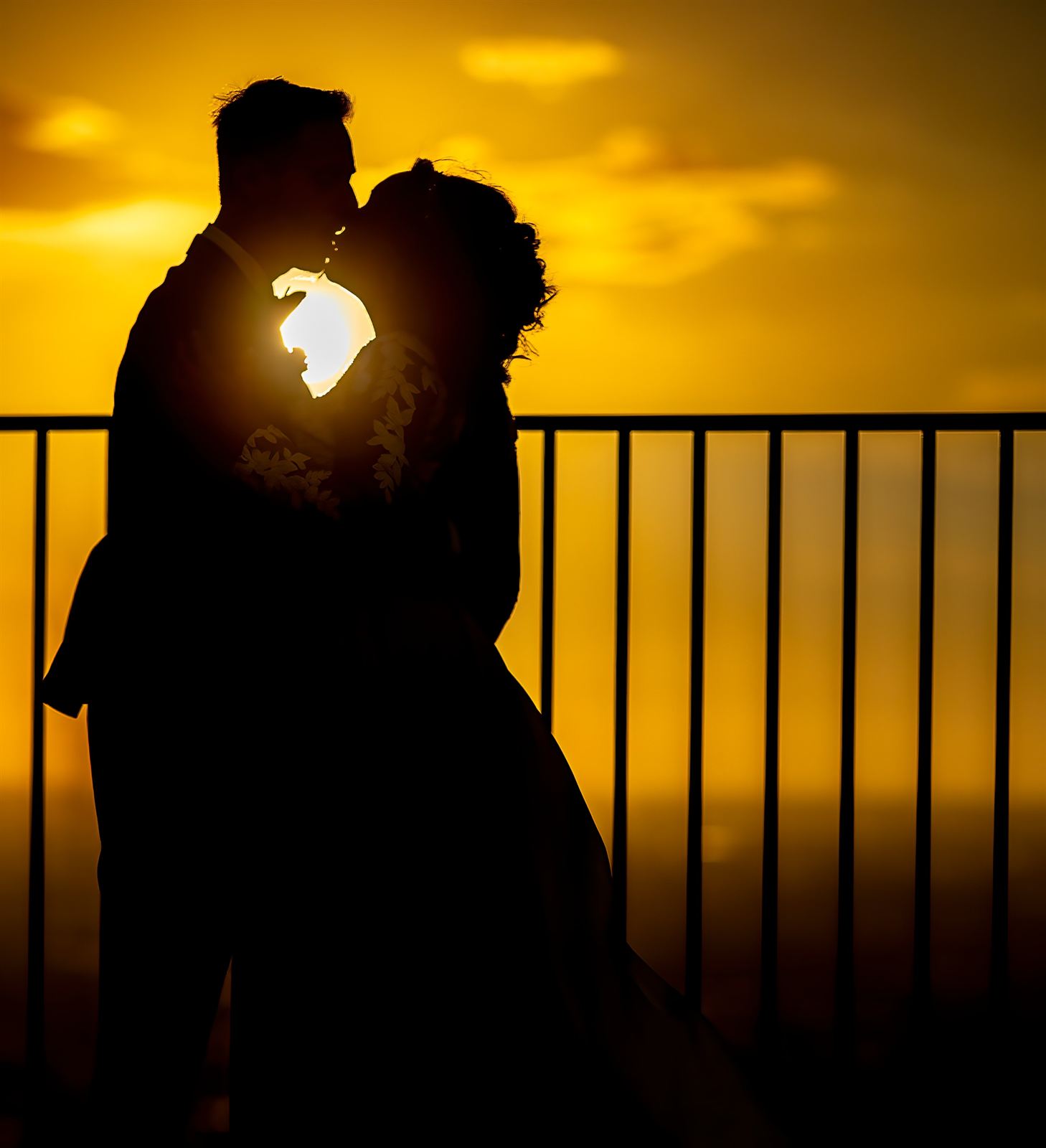 Silhouette degli sposi che si baciano controluce al tramonto