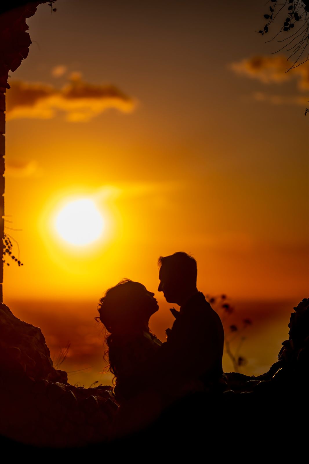 Silhouette degli sposi al tramonto, incorniciata dalla roccia